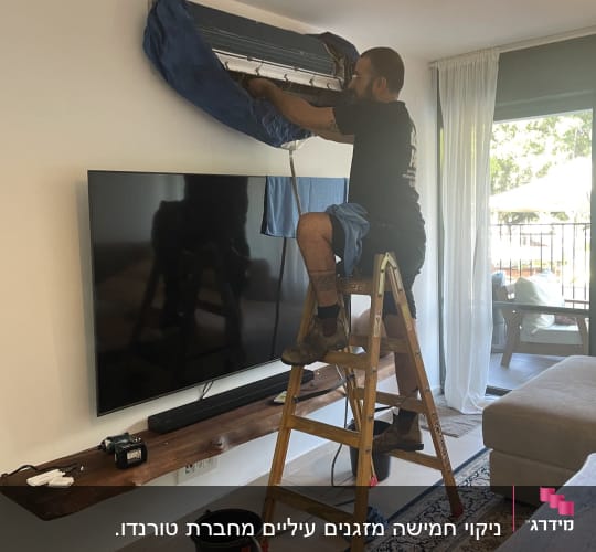 אדם על סולם מתקין מזגן על קיר